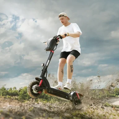 Person wearing a helmet and casual outdoor clothing riding an Isinwheel GT2 on a dirt trail, with dust rising behind the rear wheel.